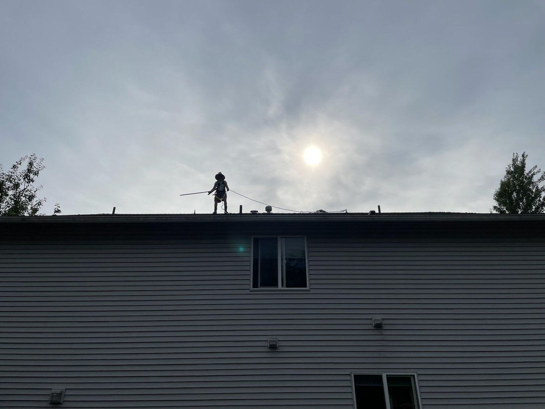 Technician working on a rooftop, silhouetted against the sky